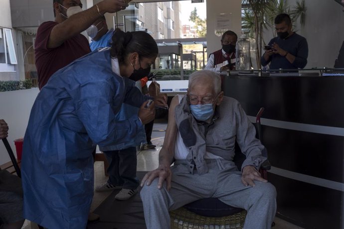 18 February 2021, Mexico, Mexico City: Nurse Elena Tello vaccinates an elderly man with a dose of AstraZeneca coronavirus vaccine. City medical workers come to an elderly residence to administer people who do not have the opportunity to visit vaccinatio