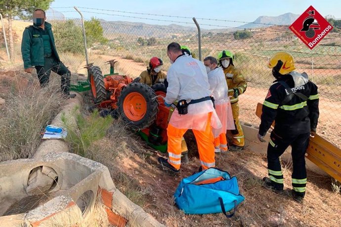 Bomberos trabajan para rescatar a la persona atrapada en el tractor