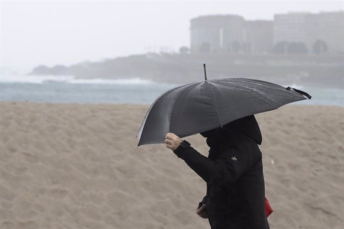 Una persona camina por el paseo marítimo de A Coruña, Galicia (España), a 30 de enero de 2021. Este sábado Galicia está afectada por una borrasca denominada 'Justine' que ha dejado cielos cubiertos con precipitaciones, localmente tormentosas.