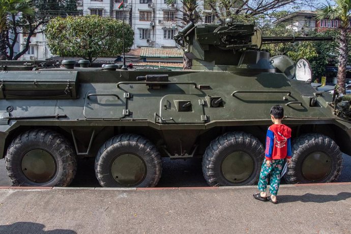 Un niño juega junto a un vehículo militar en Rangún
