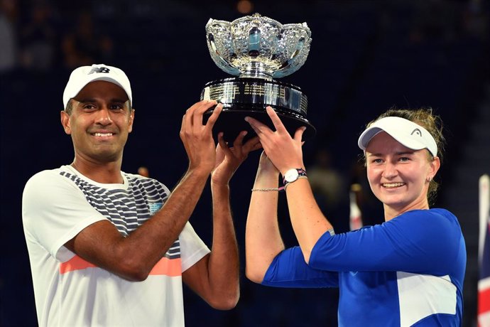 Barbora Krejcikova of the Czech Republic and Rajeev Ram of the United States raise the trophy after winning the mixed doubles final against Matthew Ebden and Samantha Stosur of Australia on day 13 of the Australian Open tennis tournament at Rod Laver Ar