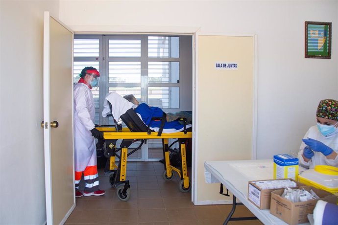 Una sanitaria traslada en camilla a una persona mayor para ser vacunada con la vacuna de Pfizer en el Polideportivo Municipal, en Villafranca De Los Barros.