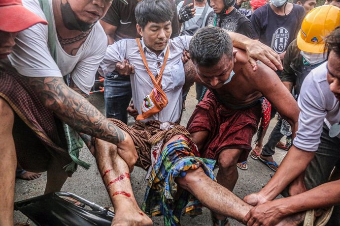 20 February 2021, Myanmar, Mandalay: Protesters carry a wounded man after police and military open fire on protesters during a demonstration against the military coup and the detention of civilian leaders in Myanmar. Photo: Kaung Zaw Hein/SOPA Images vi