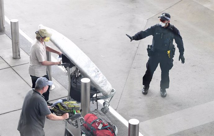 Archivo - A police officer instructs a returning passenger to stop after arriving on a special Nepal Air flight repatriating Australian and New Zealanders from overseas, in Brisbane airport, Thursday, April 2, 2020. The chartered flight out of Nepal had