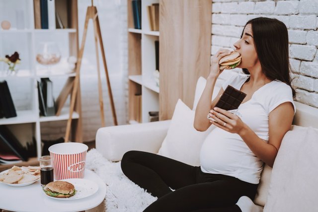 Archivo - Embarazada comiendo una hamburguesa.