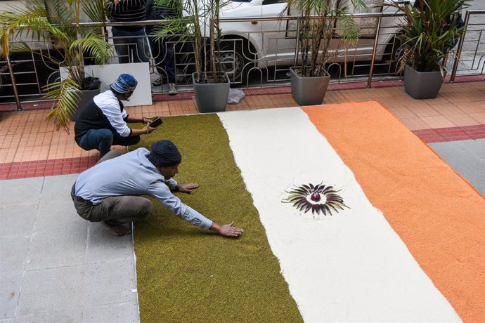 Dos agricultores elboran la bandera de India con legumbres.