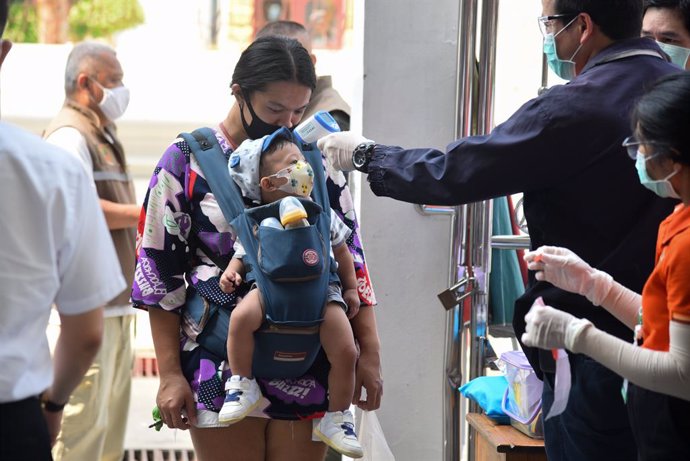 Archivo - 23 April 2020, Thailand, Bangkok: A baby has his temperature checked as a protective measure against the Coronavirus (Covid-19) before entering the Wat Rakhangkhositaram Woramahaviharn monastery where Thai monks distribute food aid amid the Co