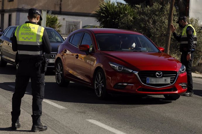 Un policía local ordena detenerse a un coche en un control en el límite entre los municipios de Murcia y Santomera, en Murcia (España) a 13 de febrero de 2021.