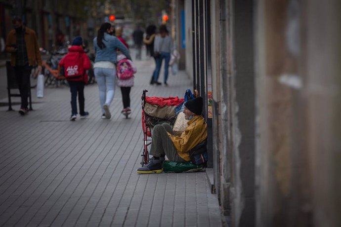 Archivo - Una persona sin techo permanece en el suelo de una calle cercana al Hospital de campaña instalado en la parroquia de Santa Anna, en Barcelona, Catalunya, (España), a 14 de noviembre de 2020. 