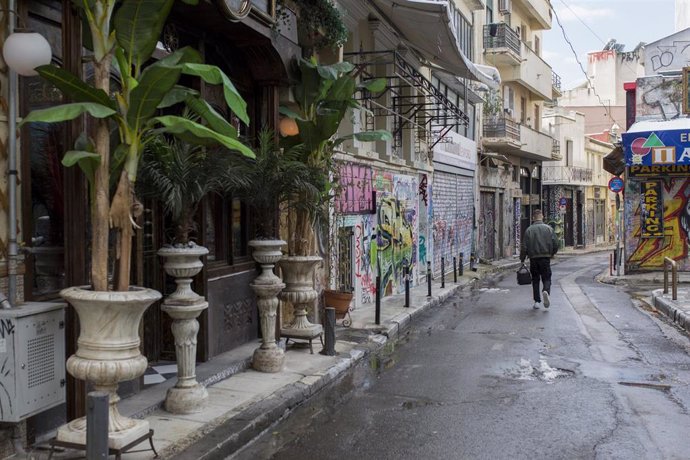 Un repartidor camina por una calle comercial cerrada por la crisis del coronavirus del barrio ateniense de Monastiraki.