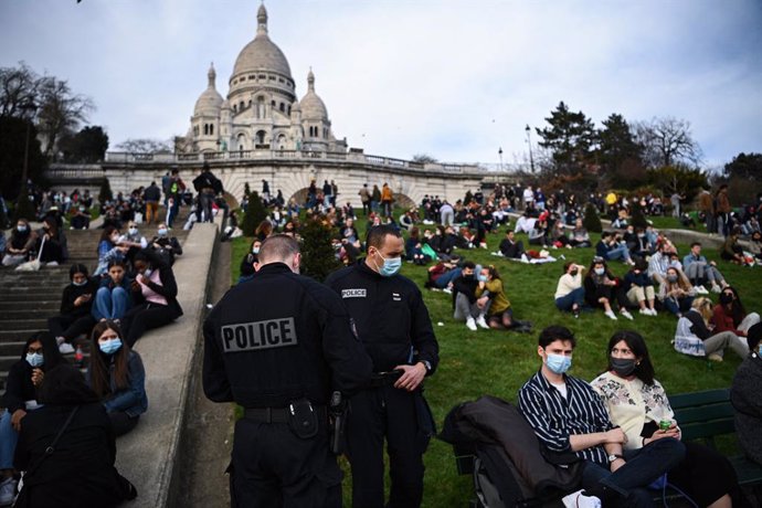 21 February 2021, France, Paris: Police officers talk to people sitting outside the Sacre Coeur Basilica. Photo: Anne-Christine Poujoulat/AFP/dpa