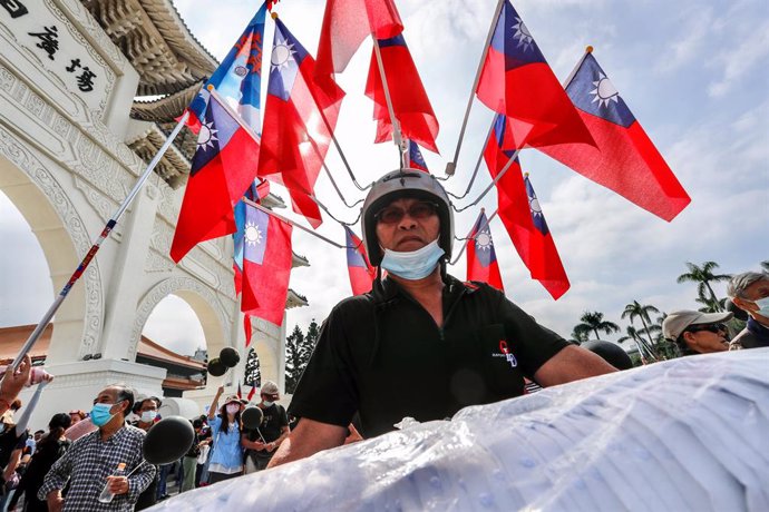 Archivo - 22 November 2020, Taiwan, Taipei: A vendor wearing a helmet with many Taiwan's national flags during a demonstration against the revoking of the operation license for CTi News, a pro Kuomintang (KMT) television company, by the National Communi