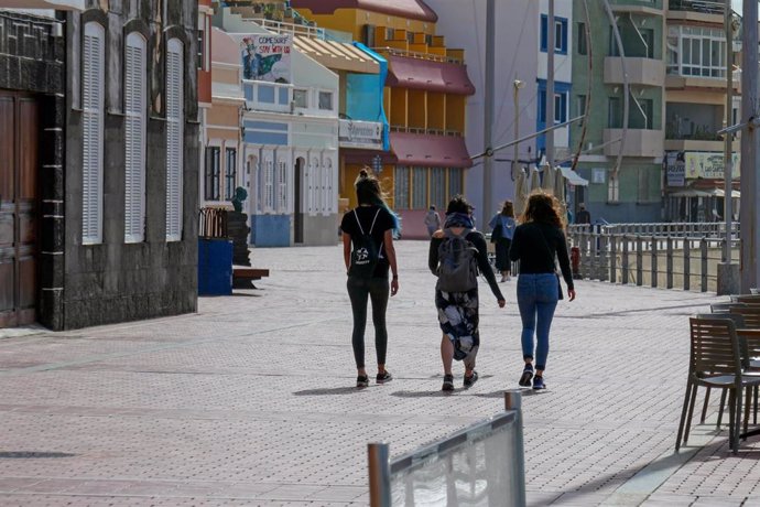 Imagen de tres jóvenes caminando por un paseo marítimo en Las Palmas de Gran Canaria