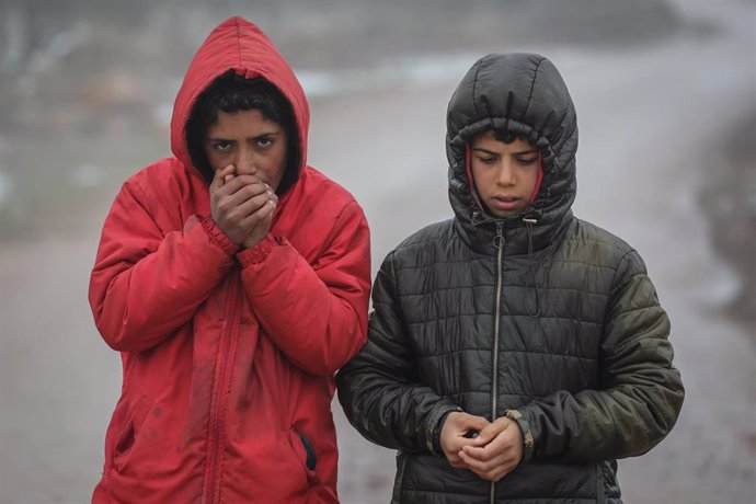 Archivo - Varios niños se calientan las manos en el campo de refugiados de Barisha, al norte de Siria.