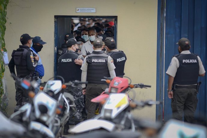 23 February 2021, Ecuador, Guayaquil: Police officers are on duty at a prison after a mutiny while relatives of the inmates wait outside for information. At least 50 people have been killed in several prison mutinies in Ecuador, according to police on T