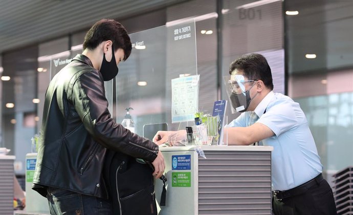 Archivo - Un pasajero muestra el certificado de un resultado negativo de un test de coronavirus a un empleado del aeropuerto internacional de Incheon, en Corea del Sur