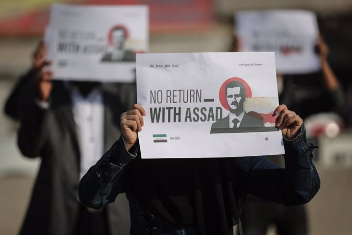 Archivo - 12 November 2020, Syria, Sarmada: Internally displaced persons and employees of civil society organizations hold placards demanding Syrian President Bashar al-Assad to step down so that they can return, during a protest against the internation