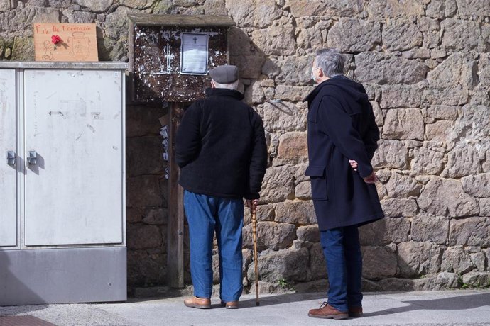 Dos hombres leen una esquela en una calle del municipio gallego de Guitiriz, en Lugo, Galicia (España), a 17 de febrero de 2021. Esta localidad gallega ha contabilizado un total de 123 positivos en los últimos 14 días, lo que sitúa su incidencia acumula