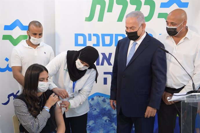 HANDOUT - 09 February 2021, Israel, Zarzir: Israeli Prime Minister Benjamin Netanyahu (2nd R) watches as a woman receives a does of the COVID-19 vaccine during his visit to the Clalit Health Services. Photo: Amos Ben-Gershom/GPO/dpa - ATTENTION: editori