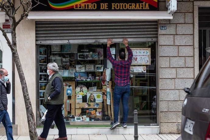 Un hombre levanta la cortina metálica de un comercio en Badajoz, Extremadura (España)
