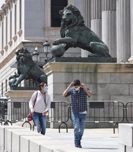 Archivo - Una pareja con mascarillas pasa por delante de la fachada del Congreso de los Diputados