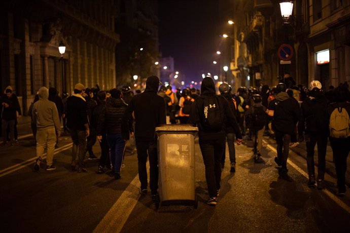 Joves violents arrosseguen una galleda d'escombraries després de la manifestació contra l'empresonament del raper i poeta Pablo Hasel, a Barcelona, Catalunya (Espanya), a 19 de febrer de 2021.