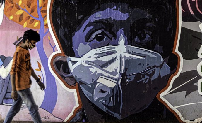 Archivo - Una persona junto a un mural en India durante la pandemia de coronavirus