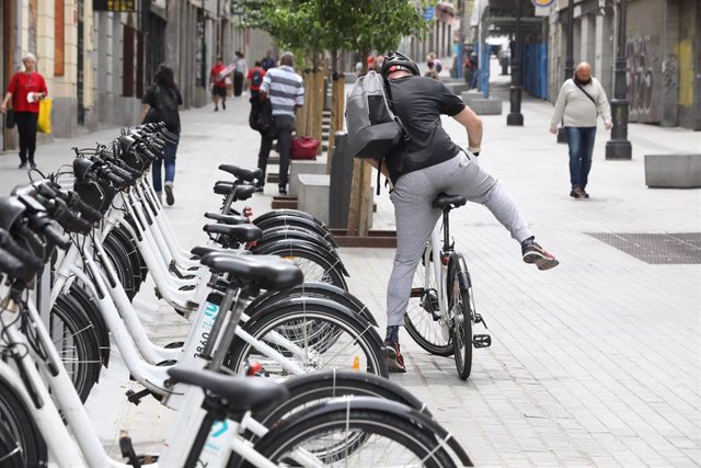Archivo - Un hombre coge una bicicleta de bicimad aparcada en una calle de la capital 