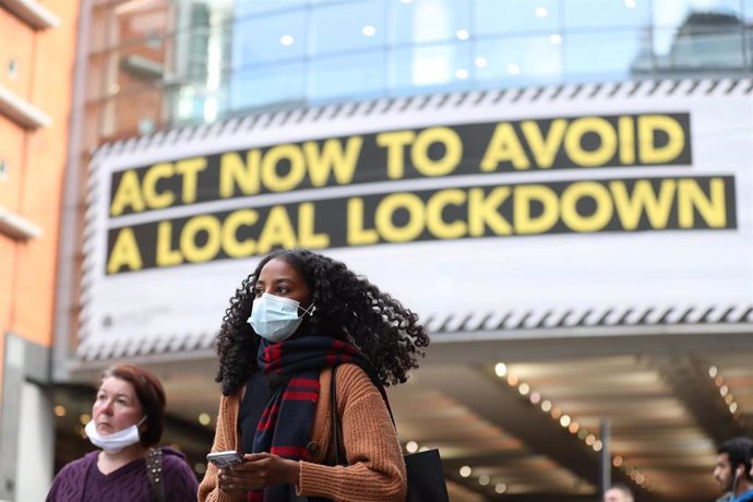 Archivo - 20 October 2020, England, Manchester: A woman wears a face mask walks past by a sign rgarding the upcoming lockdown in Manchester. Greater Manchester will be placed under stricter coronavirus controls after last-ditch talks with the UKPrime M