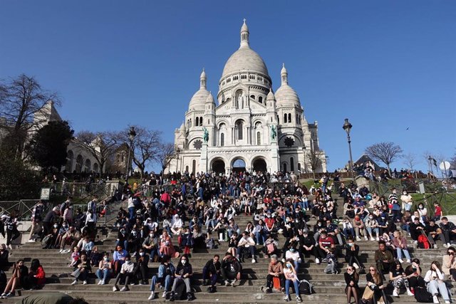 Personas sentadas ante la Basícila del Sacre Coeur en París