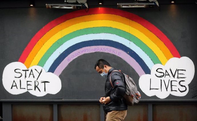 Un hombre con mascarilla pasa por delante de un mural dedicado a la pandemia de COVID-19 en Londres, la capital de Reino Unido. 