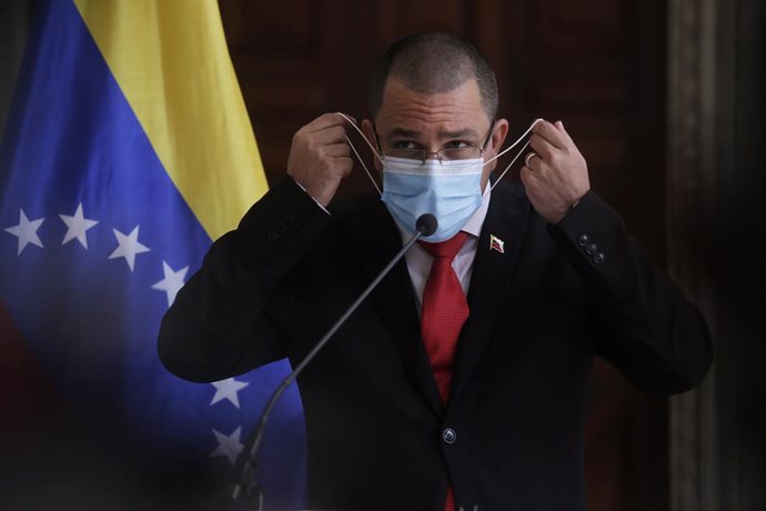 24 February 2021, Venezuela, Caracas: Jorge Arreaza, Foreign Minister of Venezuela, takes off his mask before a press conference at the Foreign Ministry. Photo: Jesus Vargas/dpa