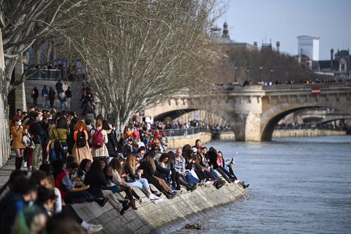 20 February 2021, France, Paris: Numerous people sit on the banks of the Seine river during the afternoon. Photo: Anne-Christine Poujoulat/AFP/dpa