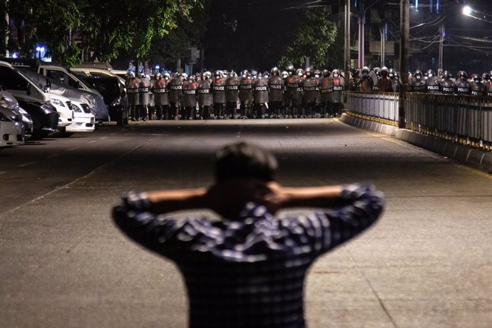 25 February 2021, Myanmar, Yangon: A demonstrator stands in front of police officers blocking the road as protesters continue to take to the streets to demonstrate against the military coup and detention of civilian leaders in Myanmar. Photo: Theint Mon