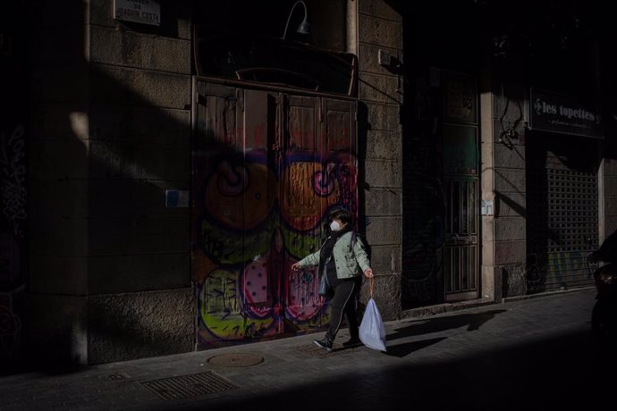 Archivo - Una mujer camina con una bolsa de basura por una calle del centro de Barcelona, Catalunya (España), a 26 de octubre de 2020.