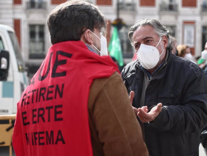 El portavoz socialista, Pepu Hernández, conversa con un hombre que acude con una camiseta donde se puede leer "Que retiren el ERTE de Ifema".