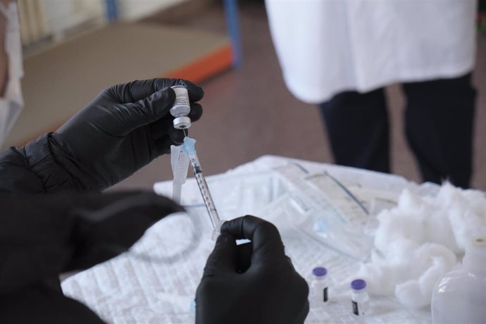 Archivo - Un trabajador sanitario prepara una de las primeras vacunas de Pfizer-BioNTech contra la Covid-19 antes de inyectársela uno de los usuarios de la Vivienda 