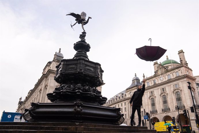 29 January 2021, United Kingdom, London: David Field throws an umbrella into the air, as he takes advantage of a near empty Piccadilly Circus during England's third national lockdown to curb the spread of coronavirus. Photo: Dominic Lipinski/PA Wire/dpa