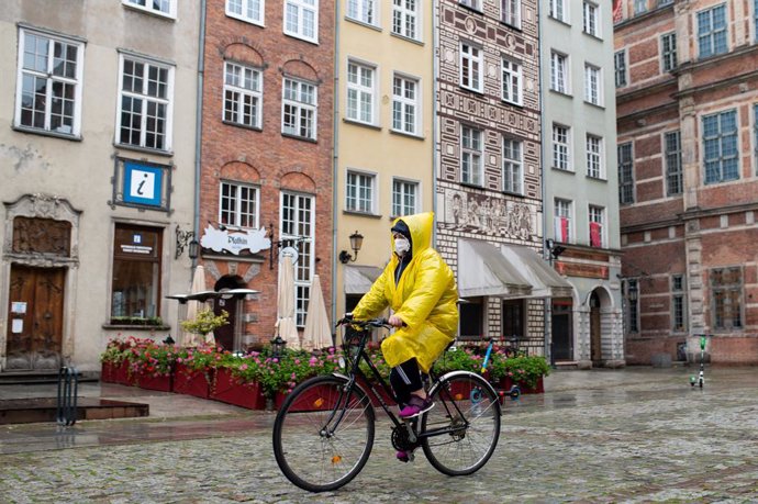 Archivo - 21 October 2020, Poland, Danzig: A woman wearing a face mask rides a bicycle on Dluga Street. Poland reported 12,107 new daily coronavirus cases on Thursday, the highest number since the beginning of the pandemic, with fresh restrictions set t