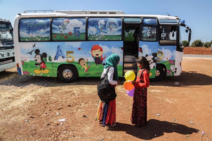 Archivo - 22 September 2019, Syria, Hazano: Syrian children are seen outside a bus which is converted into a classroom. Local teachers have invented the mobile schools to provide displaced children from rural Idlib and Hama countryside with an education