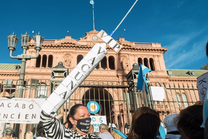 27 February 2021, Argentina, Buenos Aires: A protester holds a replica of a huge syringe during a protest against the Argentinian government after the VIP vaccine rollout scandal. The government published a list of 70 public figures who have already rec