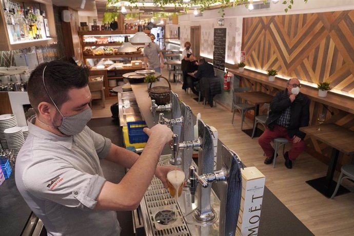 Un camarero llena un vaso de cerveza en un restaurante 