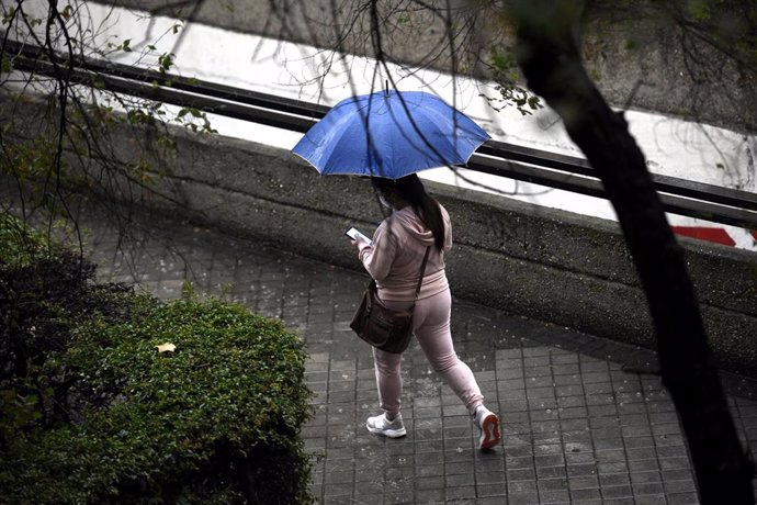 Archivo - Una persona camina bajo la lluvia protegida con un paraguas, en Madrid (España) a 24 de septiembre de 2020. La ciudad ha registrado un chubasco intenso este jueves entre las 08.30 y las 10.00 horas en el que se han acumulado entre 17 y 19 litr