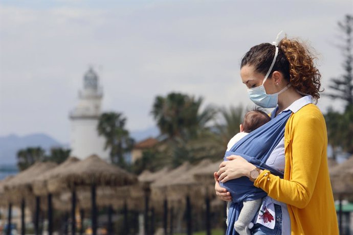 Archivo - Una mujer protegida con una mascarilla da un paseo con su bebé en la playa de La Malagueta el primer día en el que los menores de 14 años pueden salir, en Málaga (Andalucía ,España) a 26 de abril de 2020. (Foto de archivo).
