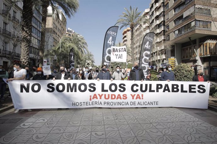 Hosteleros de Alicante participan en una manifestación con una pancarta donde se puede leer "No somos los culpables, ¡Ayudas ya!" como signo de protesta para denunciar el fracaso del Plan Resiste y la necesidad de la reapertura.
