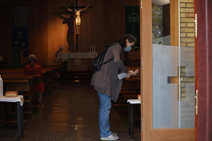 Archivo - Una mujer utiliza el gel hidroalcohólico en la entrada de una parroquia.