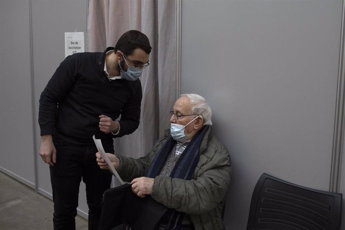 Un anciano hace una consulta mientras espera su turno para vacunarse.