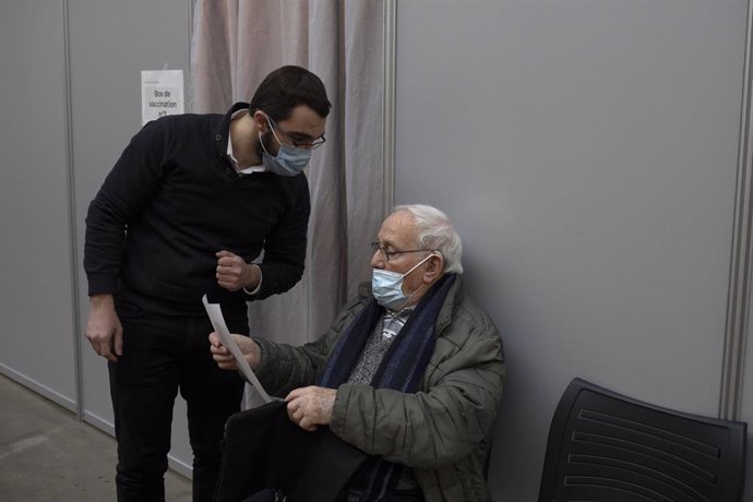 Un anciano hace una consulta mientras espera su turno para vacunarse.