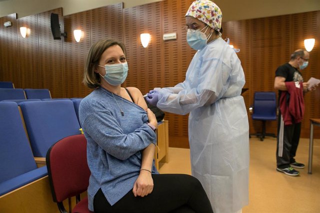 Una profesional sanitaria administra la primera dosis de la vacuna AstraZeneca contra la COVID-19 a Belén López Moreno, la primera profesora en recibir la vacuna contra el virus, en el Hospital de Mérida