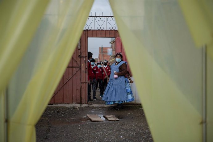 11 February 2021, Bolivia, Palcoco: Students wear face masks line up at the entrance of the Bolivian-Japanese school where they are sprayed by the facility's staff against the spread of the coronavirus. The school has been allowed to provide partial-pre